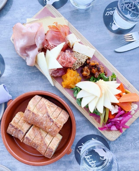 Photo of Txikiteo Charcuterie combo board with meat and cheese, pickled vegetables, mustards,  and bread from Acme Bakeshop taken from looking directly down at the table.