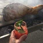 Bloody Mary toasting a full lamb that is roasting over a fire