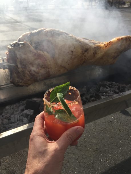 Bloody Mary toasting a full lamb that is roasting over a fire