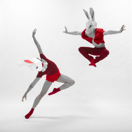 Ballet Dancers in paper, geometric bunny masks and red clothing.