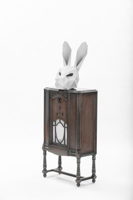 geometric paper white bunny mask sitting on top of an old wooden music player